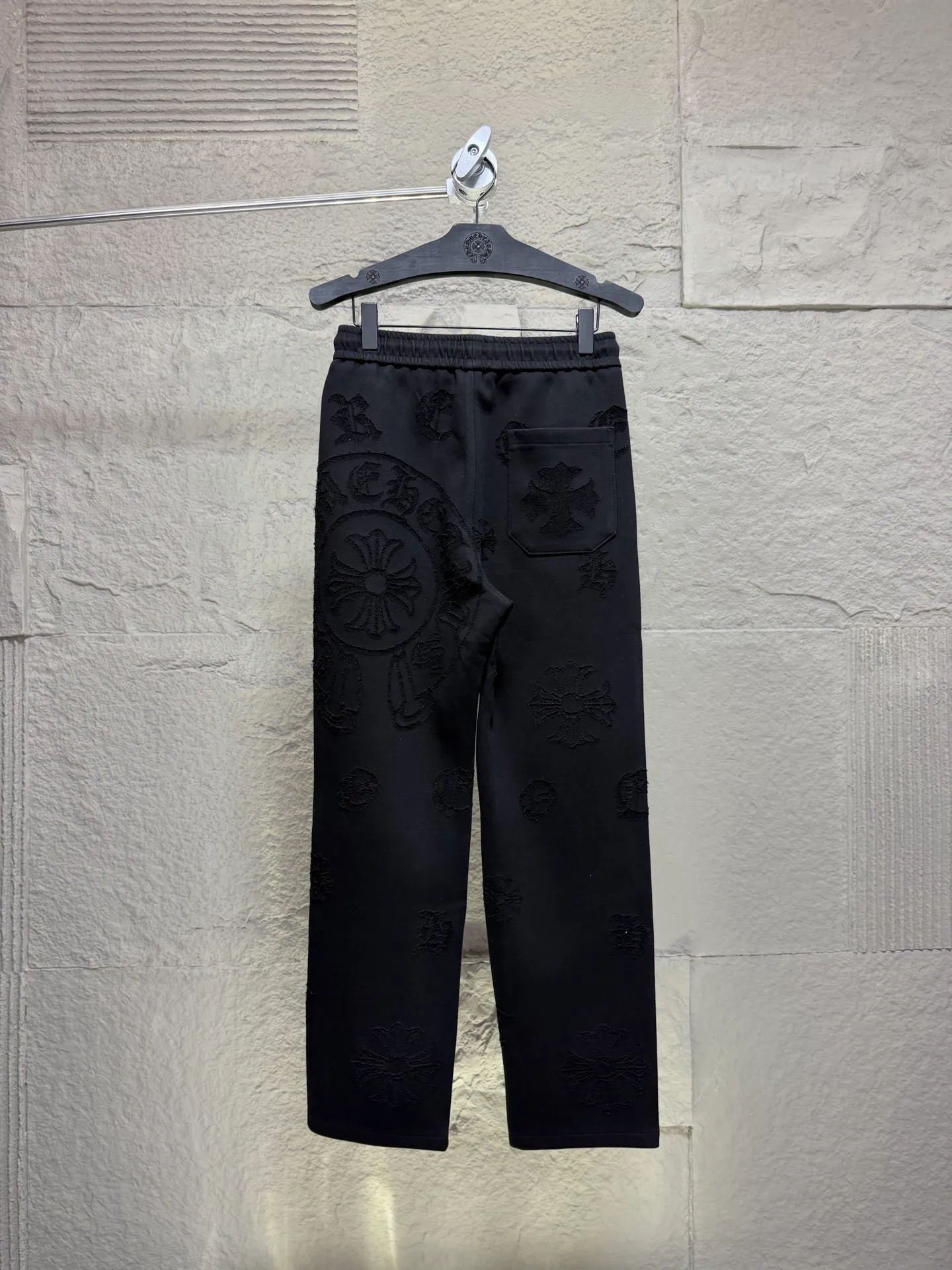 CH/Cro Heart 2026ss Burnt Flower Straight-leg Sweatpants Classic heavy-weight sweatpants with gray tones, Retro street style full-fitting, direct recognition, same style for men and women. ●Three-dimensional patchwork technology: The whole body is covered with Gothic letters + cross flower totems, using raw edge patchwork embroidery, with a mustache-like old texture, and uneven and layered patterns. It is not an ordinary print, and it is durable and not easy to fall off. ●Style tailoring: Loose, straight and wide-legged version, modifying the shape of the legs, hiding the flesh neatly, not flattering the figure, with an online drape, and the upper body has a relaxed street tone. ●Fabric and waist: Heavy knitted terry fabric, thick and soft, with good drape; elastic drawstring waist, with branded metal engraved rope ends, easy to put on and take off, and strong waist adaptability. ●Detailed design: The side pockets are convenient for carrying items, and the back pocket is decorated with cross-pattern patches. The front and rear patterns echo each other. Every detail is highly recognizable to the brand. ●Wearing scenarios: Suitable for street wear, daily outings, and trendy wear. Paired with sweaters, denim jackets, and leather jackets, you can easily create an American retro cool style. ●The overall gray base is paired with Cream White patches, which are low-key yet impactful. They are both comfortable and trendy. Versatile sweatpants, a must-have for fashionistas, are also available at the counter. SIZE：M L XL XXL XXXL